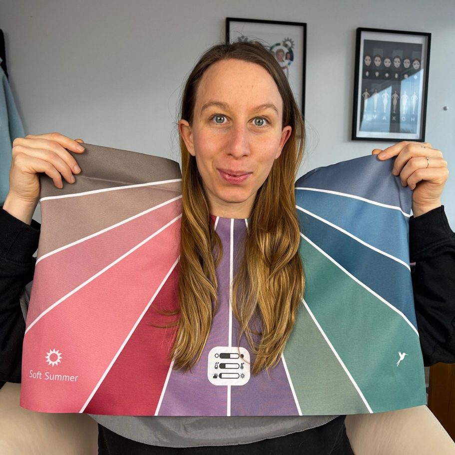 Frau hält ein großes Farbtafeltuch in verschiedenen Farbtönen vor sich.